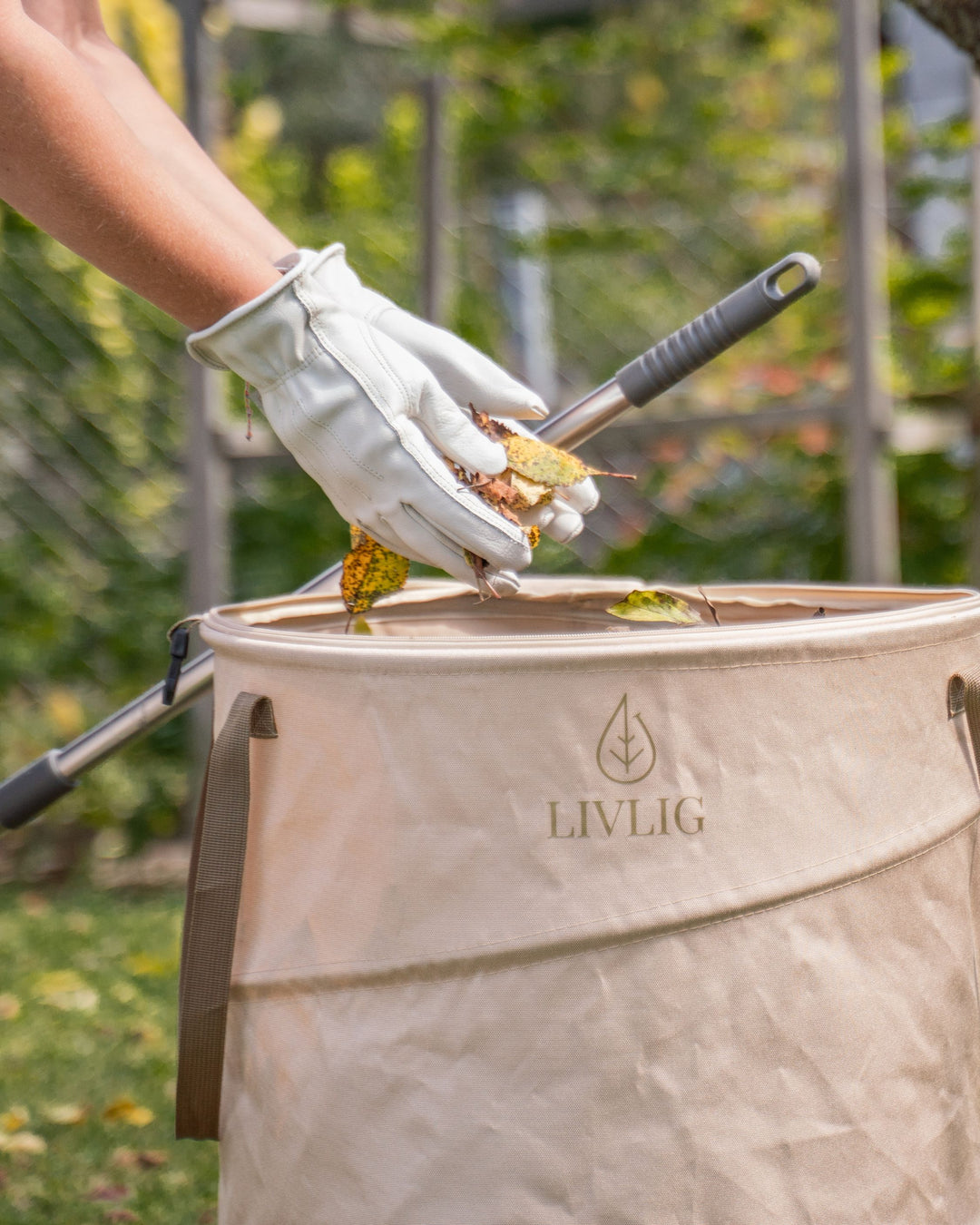 Person mit Livlig Gartenhandschuhen wirft Laub in den Livlig Laubsack.