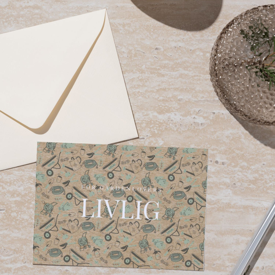LIVLIG Gutschein von LIVLIG mit Gartenmotiven auf beigem Hintergrund, neben einem Umschlag und einer Dekoschale.
