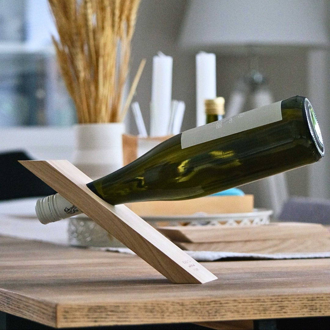 Hölzerner Weinflaschenhalter mit Flaschenetikett von LIVLIG, hält eine volle Weinflasche auf einem Holztisch.