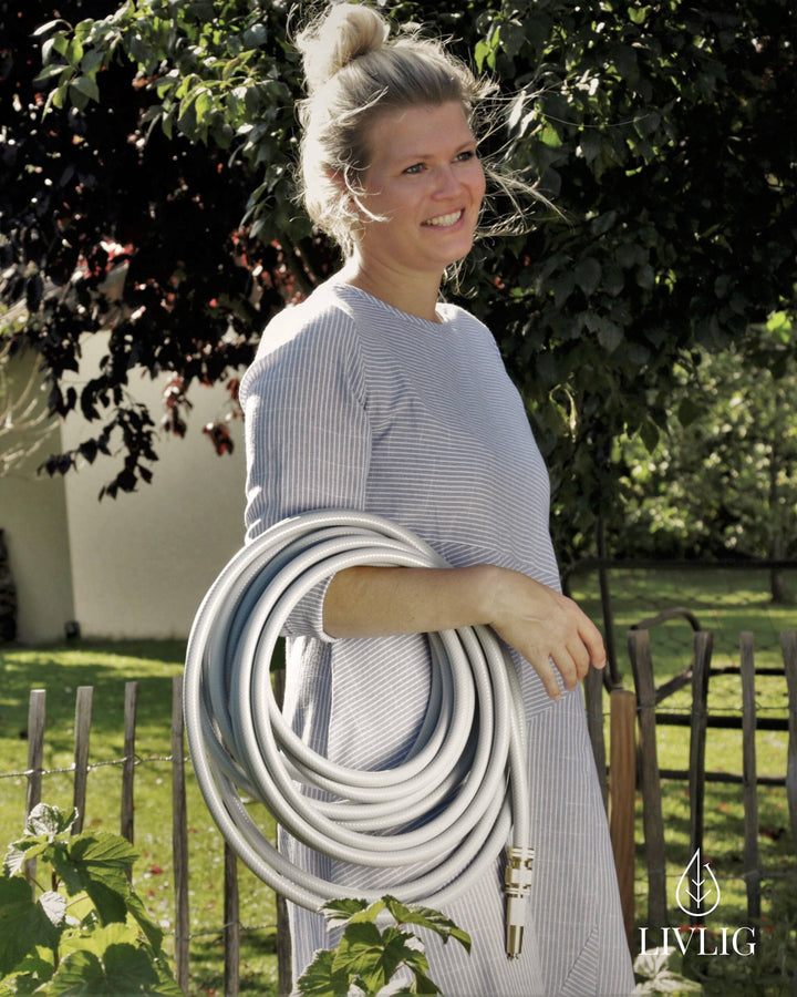 a woman holding a garden hose in her hands