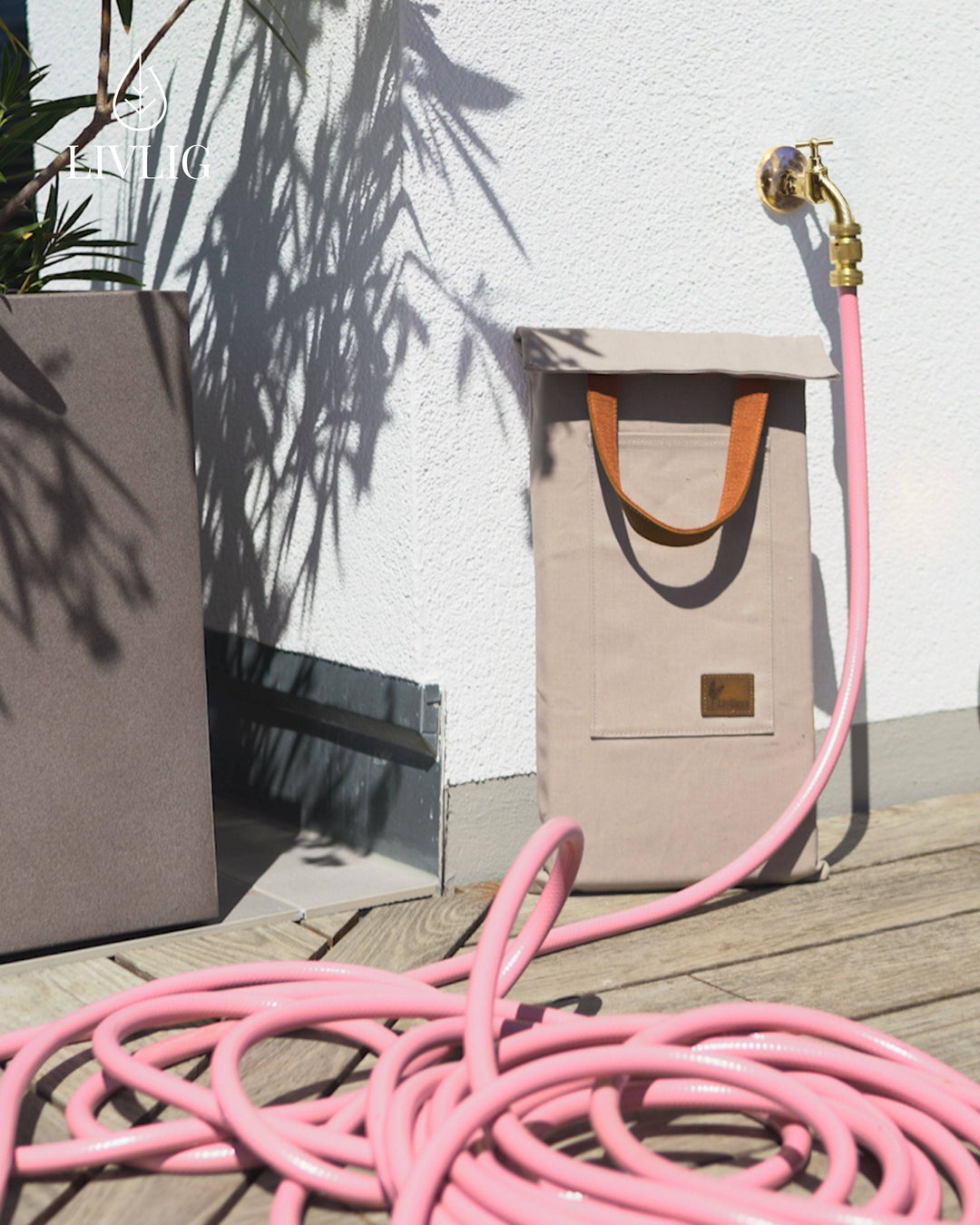 a pink hose laying on a wooden deck next to a bag