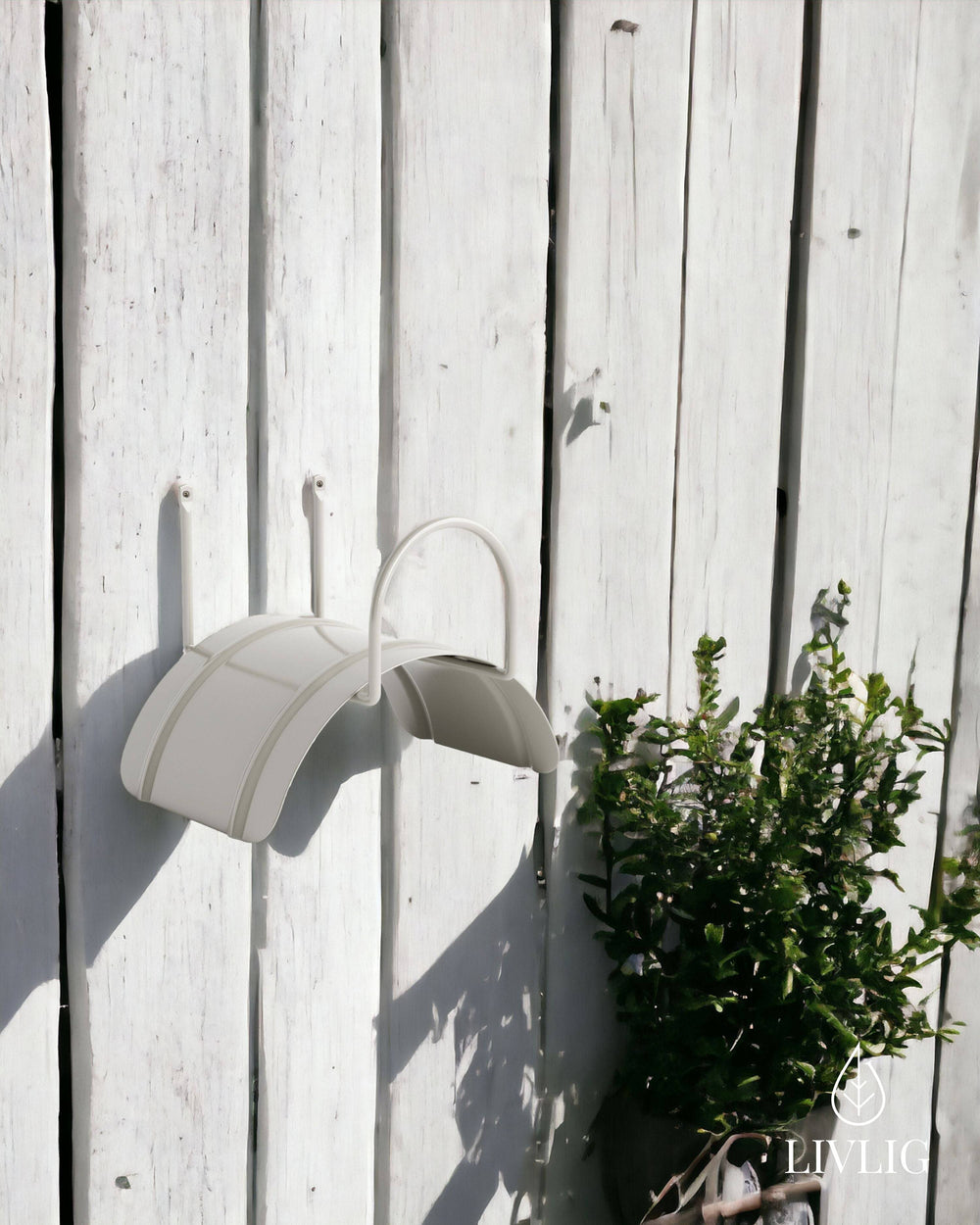 a white umbrella and a potted plant against a white fence