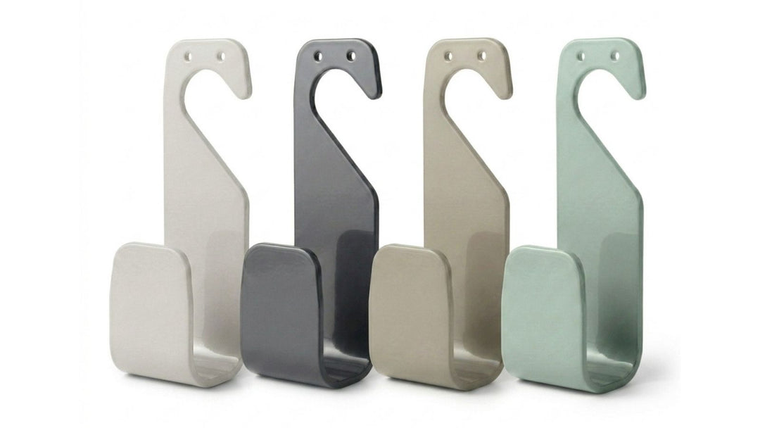 Vier S-förmige Haken in Hellgrau, Dunkelgrau, Beige und Mintgrün stehen nebeneinander auf einem weißen Hintergrund.