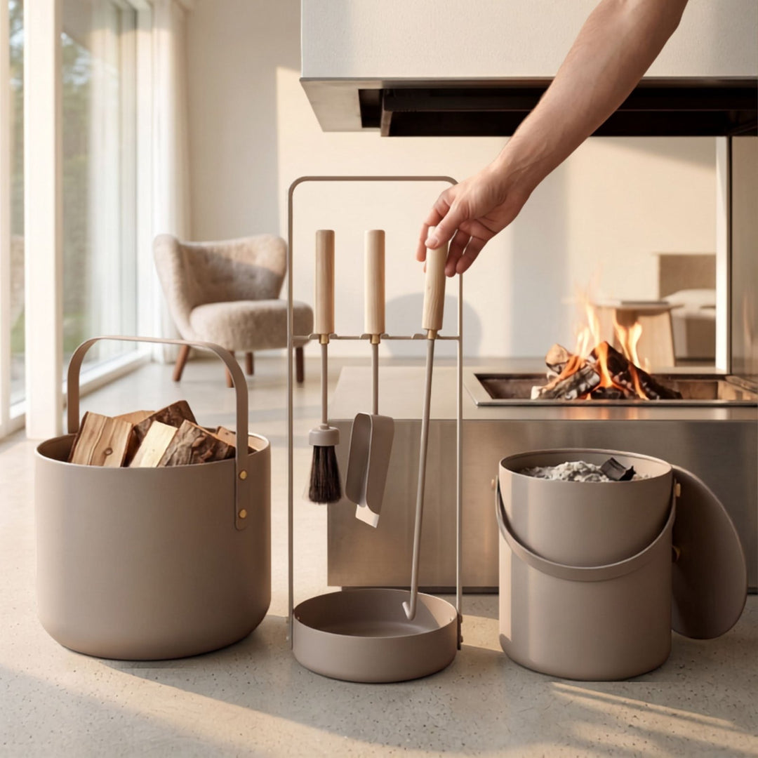 Elegantes Kaminbesteck in taupe mit Holzgriffen von LIVLIG, im Lifestyle-Setting vor brennendem Kamin, mit passenden Eimern für Holz und Asche.