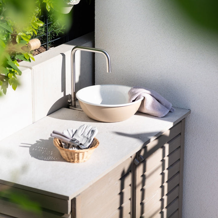 Flexibler Outdoor-Wasserhahn von LIVLIG, Installation im Außenbereich mit Waschbecken und Gartengeräten, natürliches Licht und Schatten.