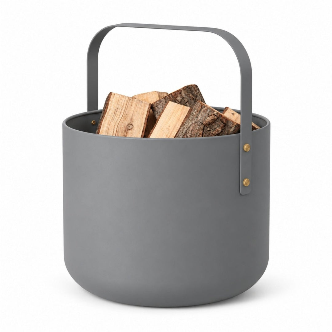 Grauer Metallkaminholzkorb von LIVLIG mit geschwungener Tragegriff und goldenen Beschlägen, gefüllt mit Holzscheiten, Frontansicht