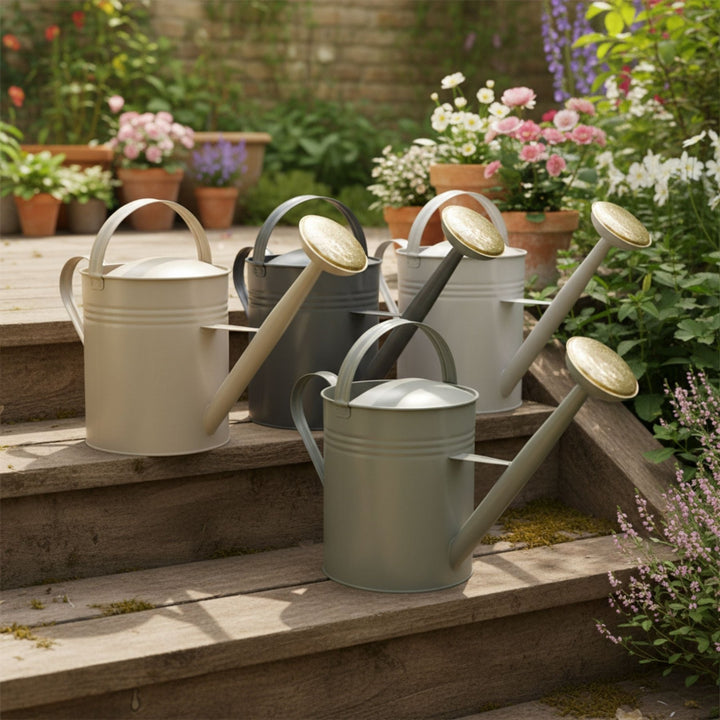 Metallgießkanne 10L mit zwei Henkeln von LIVLIG, in verschiedenen Farben auf Holzstufen im Garten.