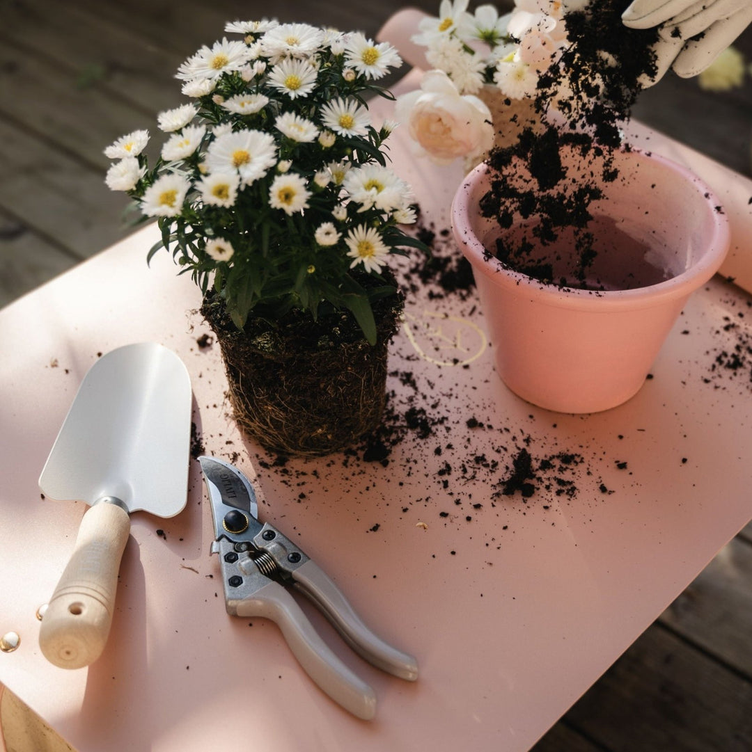 Person pflanzt auf der Livlig Pflanzmatte – daneben liegen die Livlig Gartenschere und die Livlig Handschaufel.