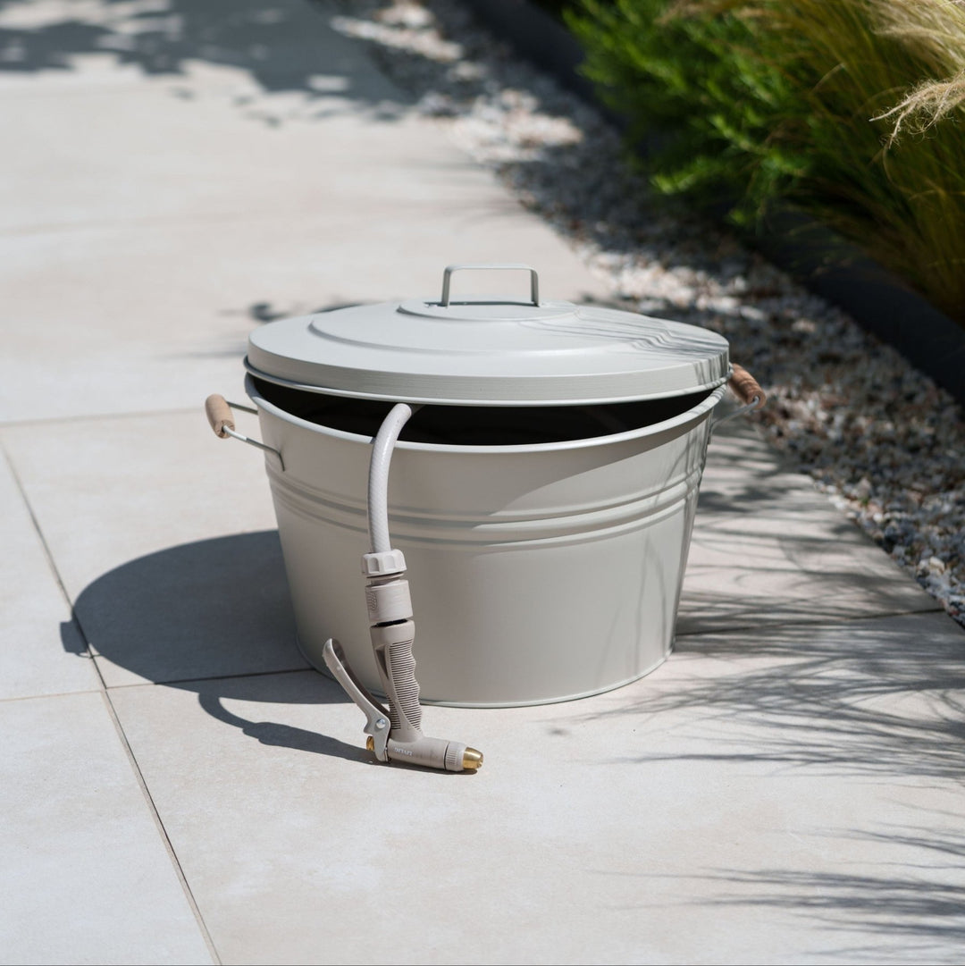 Metall Schlauchtopf von LIVLIG, mit Deckel und Schlauch auf hellen Fliesen im Freien.