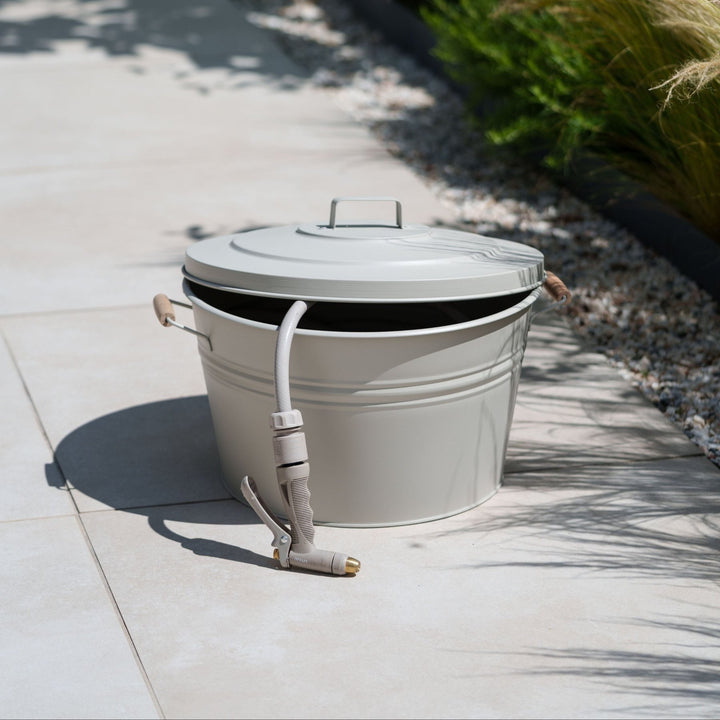 Metall Schlauchtopf von LIVLIG, mit Deckel und Schlauch auf hellen Fliesen im Freien.
