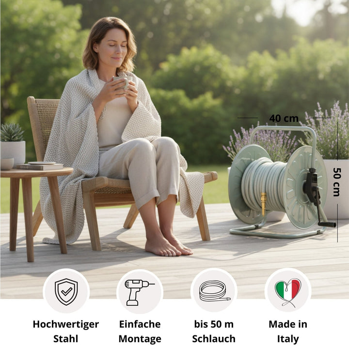 Metall Schlauchtrommel von LIVLIG, hellgrün, mit Schlauch, im Garten mit sitzender Frau mit Decke.