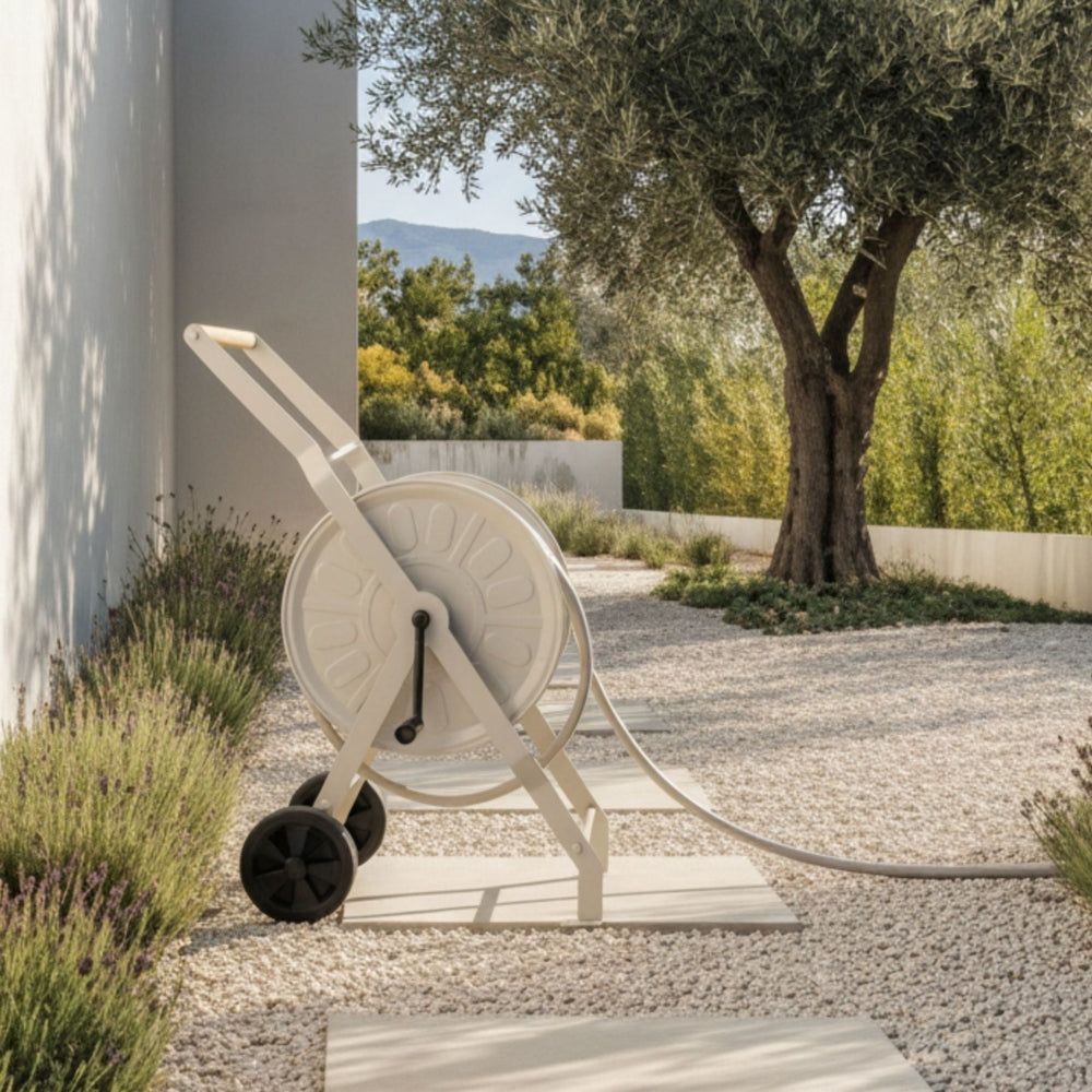 Schlauchwagen Komplettset in Gentle Greige von LIVLIG mit Holzgriff, schwarzen Rädern und hellem Schlauch auf Kiesweg.