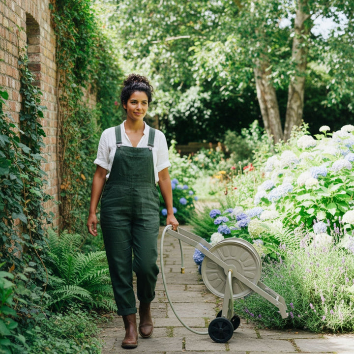 Schlauchwagen Komplettset Gentle Greige von LIVLIG mit Schlauch und Düse, im Garten von einer Frau benutzt.
