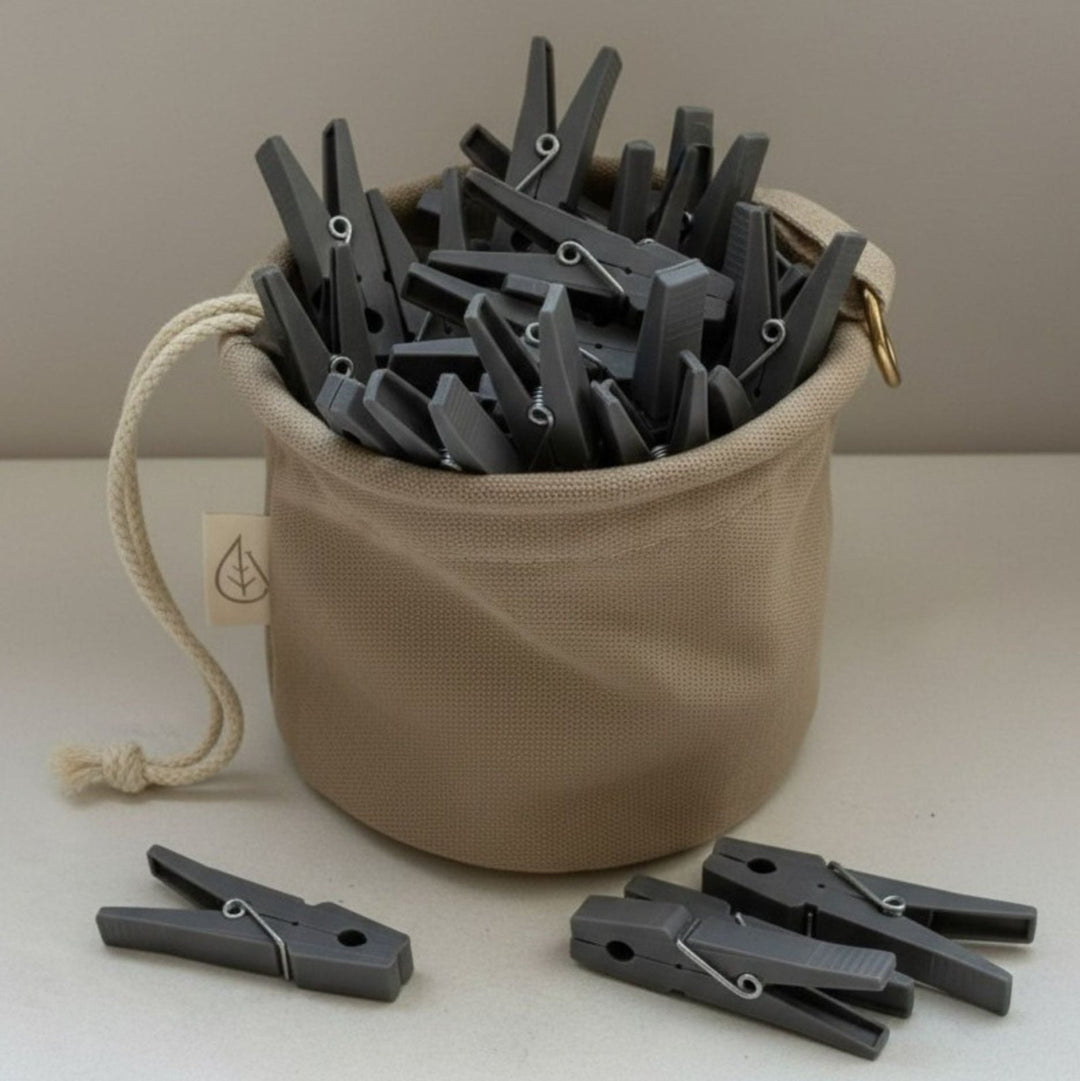 Beiger Wäscheklammerbeutel mit grauen Wäscheklammern von LIVLIG, mit Kordelzug und Label mit Blatt-Symbol.