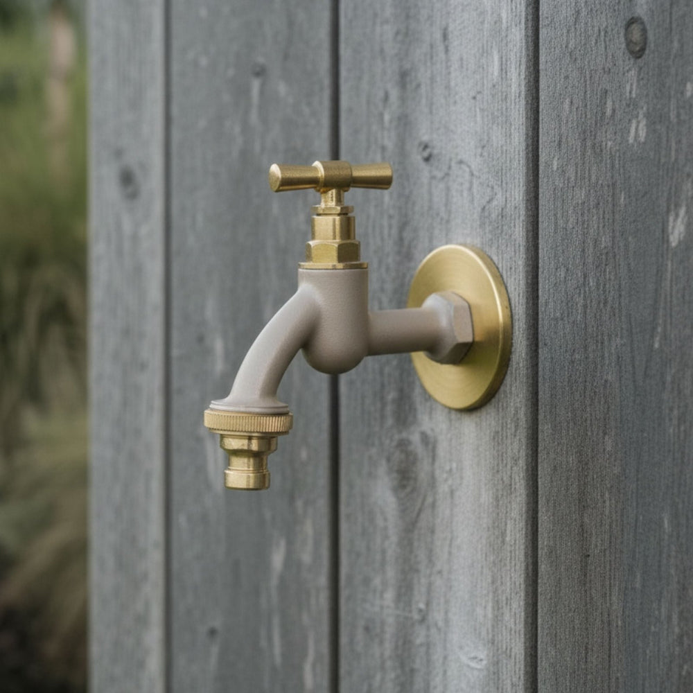 Beige-farbener Garten-Wasserhahn von LIVLIG mit Messing-Rosettengarnitur und -Griff, an grauer Holzplankenwand montiert.