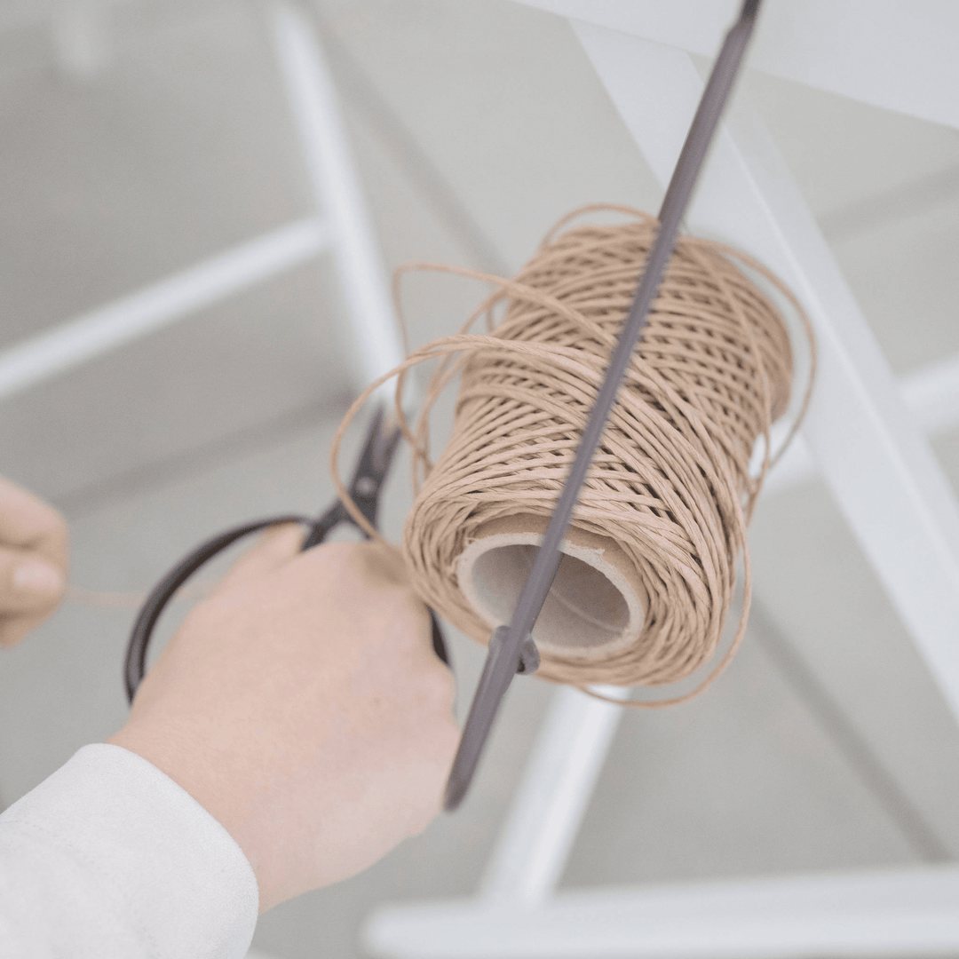 a hand holding a spool of twine and a spool of twine